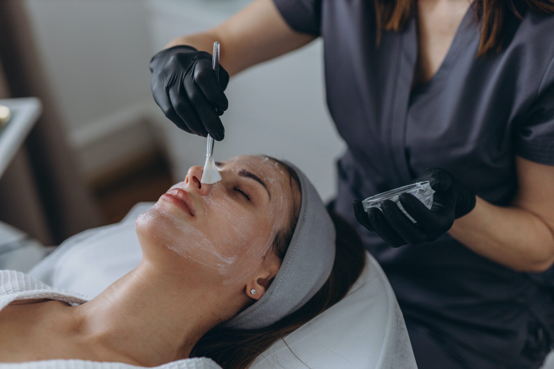 Cosmetologist performs a facial peeling procedure on a young woman. chemický peeling AlphaPeel Brno hloubkové čištění pleti a regenerace pokožky
